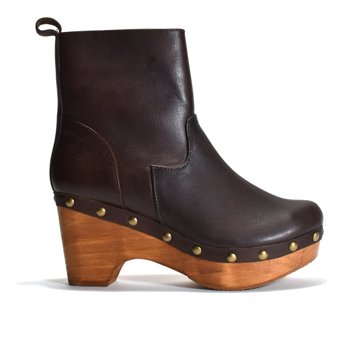 A dark brown leather ankle boot with a wooden platform and block heel, accented with brass studs and a pull loop, shown from a side profile on a white background.