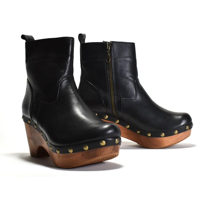 A pair of black leather ankle boots with wooden platform heels, gold-tone studs, and side zippers, shown on a clean white background.