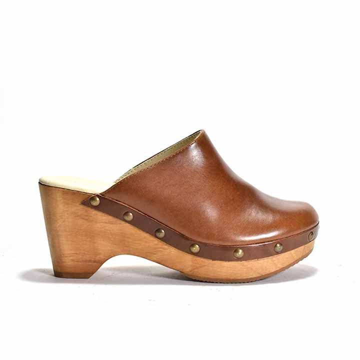 A brown leather clog with a wooden heel and platform, featuring metal eyelets 