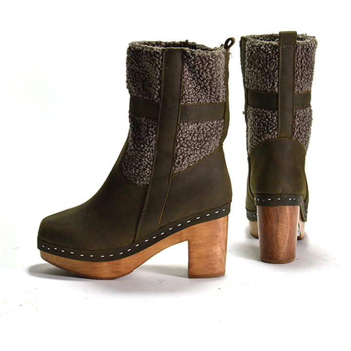 A pair of mid-calf boots with dark olive green leather, brown faux-shearling panels, and wooden block heels, shown from both the side and back angles on a white background.